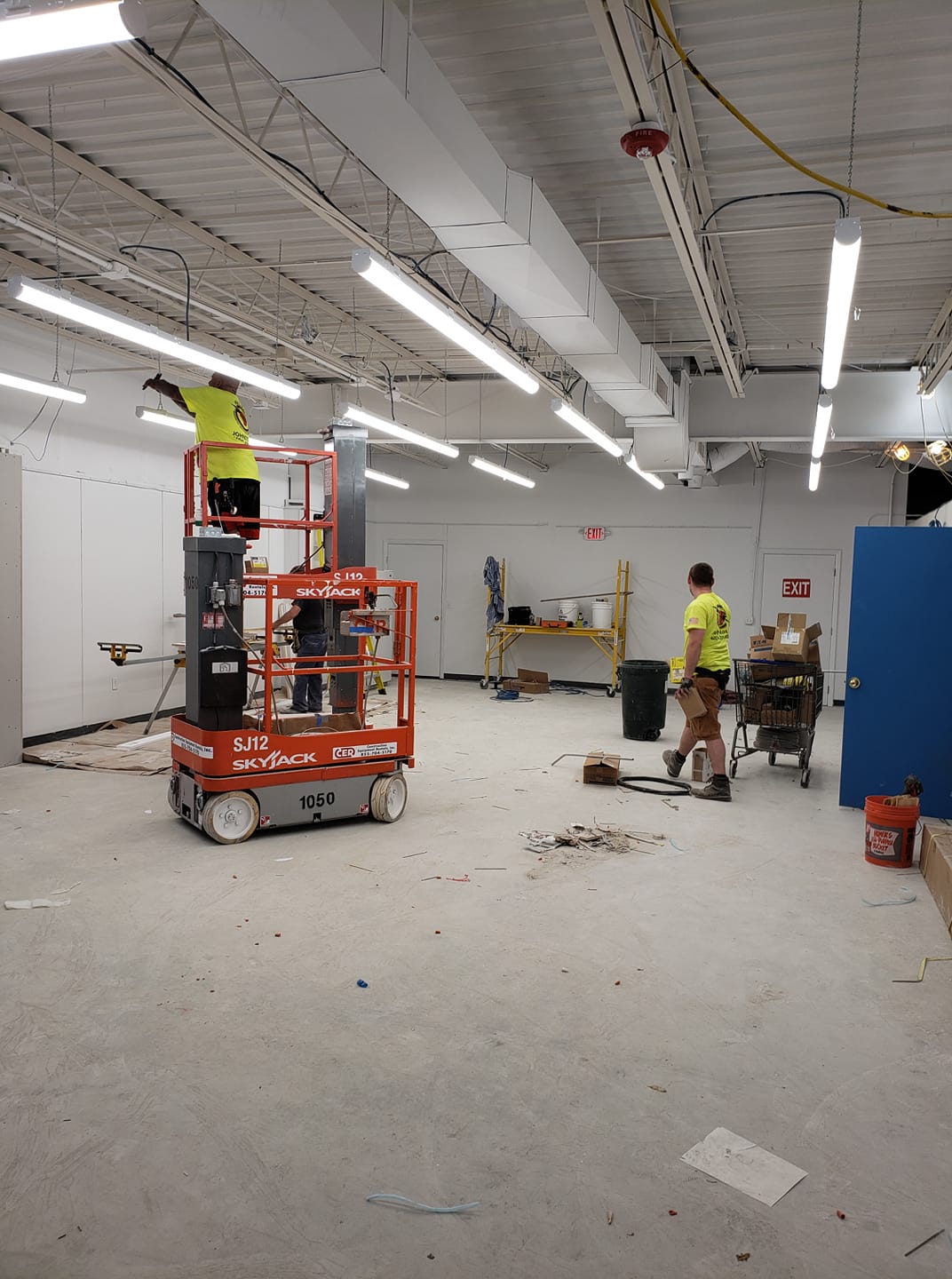 Kelco Electric crew on a lift running commercial lighting in an open warehouse space